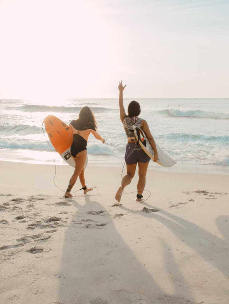 Zwei Frauen am Strand mit Surfbrettern 